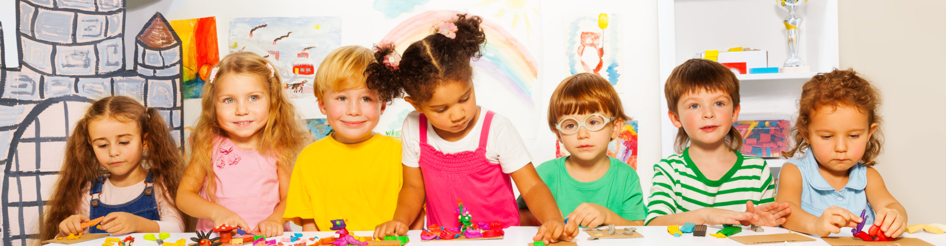 a group of preschool boys and girls play with modeling clay in class